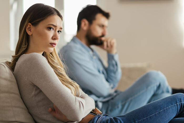 Junges Paar sitzt mit Abstand auf der Couch