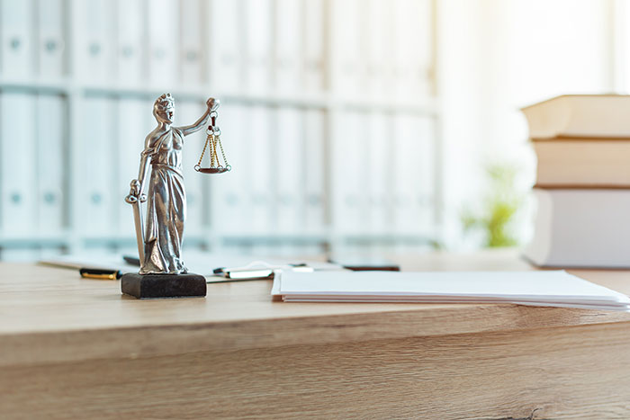 Die Figur Justitia auf einem Schreibtisch als Symbol für Rechtsanwaltskooperationen