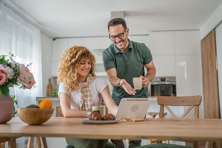 Junges Paar in der Küche mit Laptop sucht nach größerer Wohnung