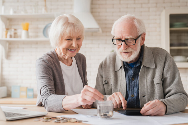 Ein älteres Ehepaar legt Münzen in eine Spardose