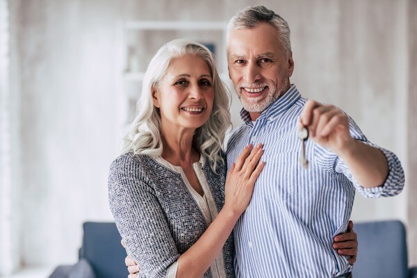 Ein älteres Ehepaar hält zeigt den Schlüssel zu Ihrer Immobilie