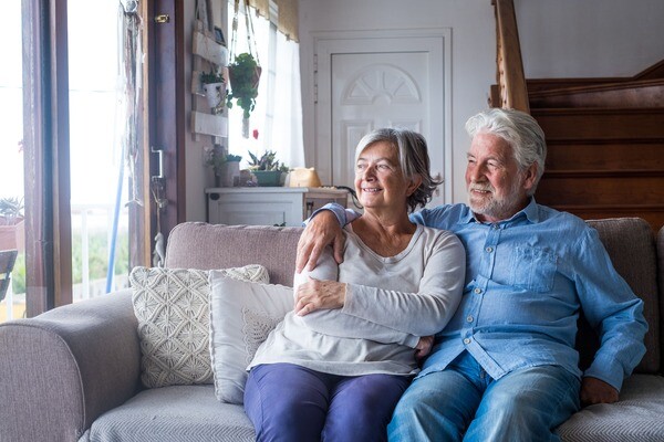 Ein älteres Ehepaar sitzt lächelnd auf der Couch