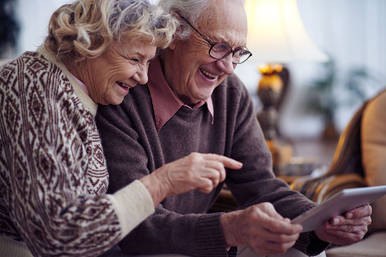 Ein älteres Ehepaar liest etwas auf einem Tablet