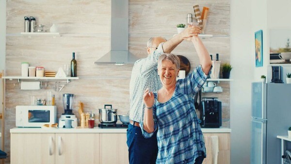 Ein fröhliches Ehepaar tanzt sorgenfrei in der Küche