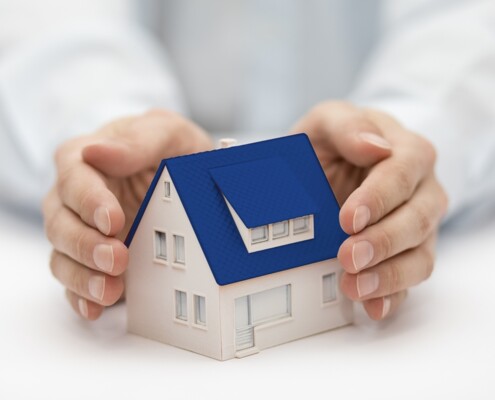Hände halten ein Miniaturhaus