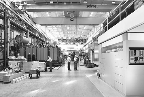 Produktionshalle mit großen Maschinen für die Produktion und Mitarbeitern bei der Arbeit