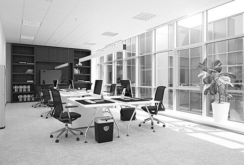 Modernes Büro mit Arbeitsplätzen, Computern und großem Bildschirm an der Wand